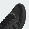 Close-up view of a black ADIDAS TYSHAWN LOW BLACK / WHITE / GOLD METALLIC skateboarding shoe with white stitching and laces, focusing on the front and side.