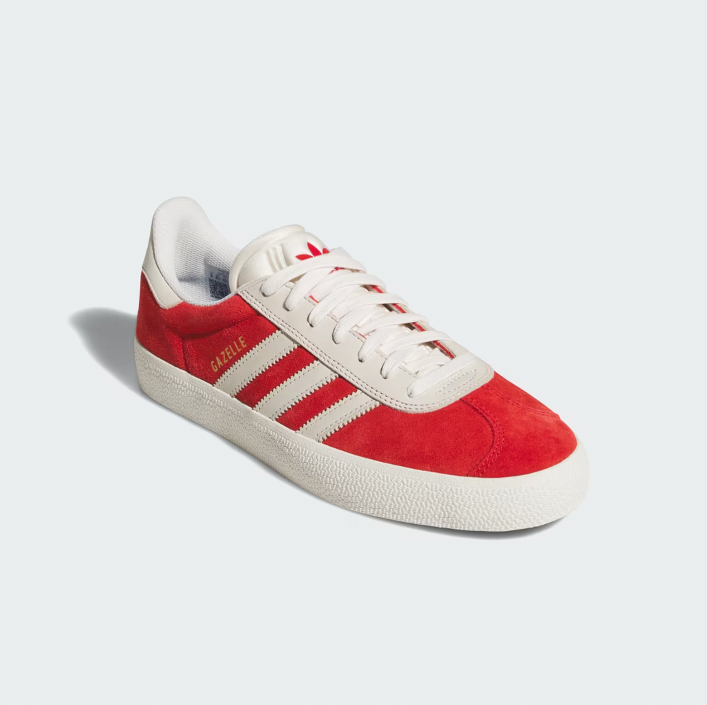 The ADIDAS GAZELLE ADV BETTER in Scarlet and Chalk White features a striking red body with classic white stripes and a smooth white sole. The word "Gazelle" is prominently displayed on the side, reflecting MNUFC's energetic style against a minimalist backdrop for a sophisticated look.