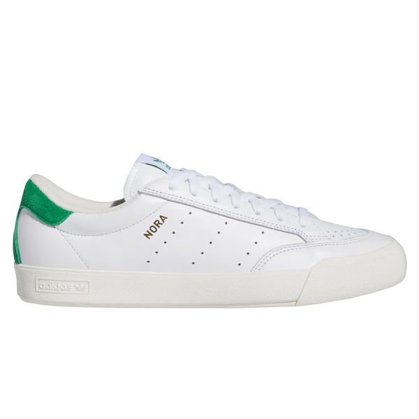 A white, slim looking leather shoe with a green suede heel tab that says "nora" in gold on the side.