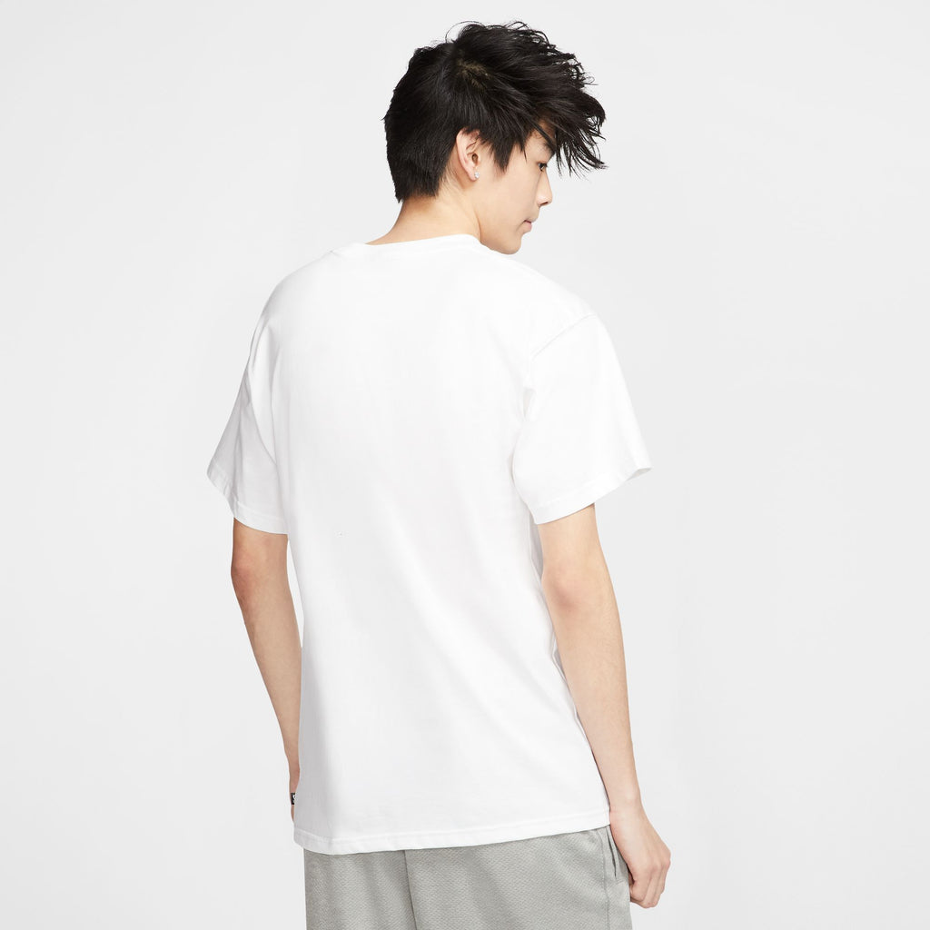 A person seen from behind wearing a plain white nike SB logo skate tee and grey pants.