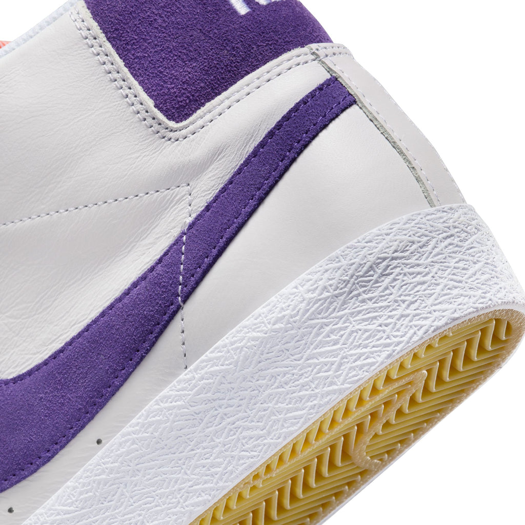 The heel of a white leather shoe with a suede purple insole.