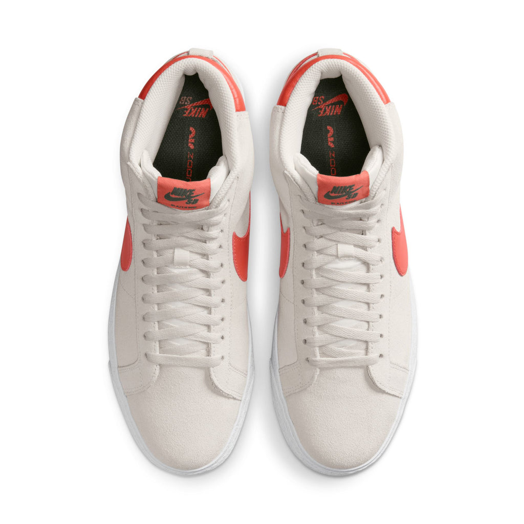 A pair of white and red Nike SB Zoom Blazer Mid skateboarder shoes viewed from above, featuring NIKE SB BLAZER MID PHANTOM / COSMIC CLAY cushioning.