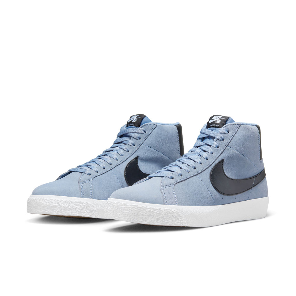 A pair of Nike NIKE SB BLAZER MID ASHEN SLATE/ BLACK blue high-top sneakers with white soles, black logo detail, and Zoom Air cushioning.