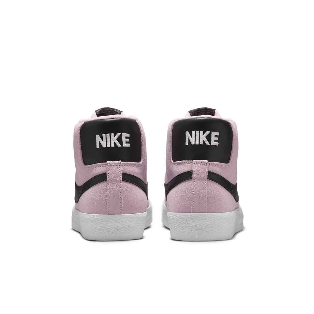 The NIKE SB BLAZER MID PINK FOAM/ANTHRACITE-WHITE-GUM YELLOW sneakers by Nike feature a pink suede upper, black heel tabs with white "NIKE" text, and classic white rubber soles, shown from the back.