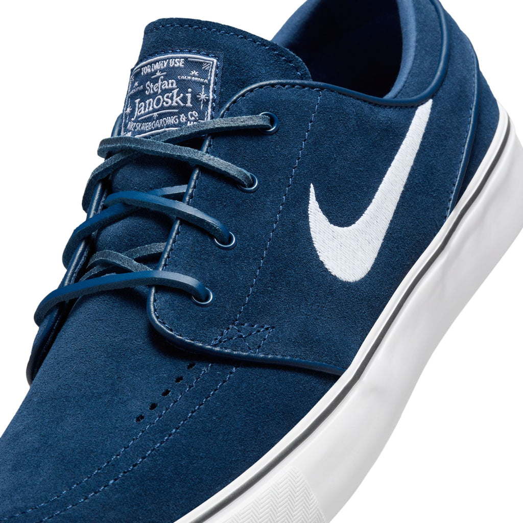 Close-up of a blue suede nike sb zoom janoski og+ navy / white sneaker with white laces and a white logo.