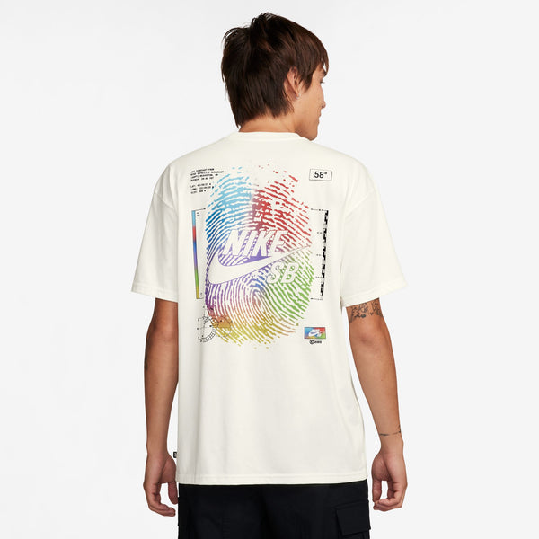 A man wearing a white nike FORCAST SKATE TEE SAIL t-shirt with a colorful graphic print and logo on the back, facing away, with a visible arm tattoo.