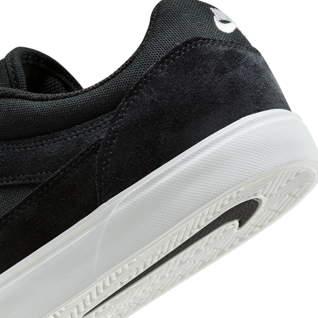 Close-up of the NIKE SB MALOR BLACK / WHITE skate shoe by Nike, showcasing the white logo on the heel and a textured sole. Its durable suede and textile construction offers an ideal blend of style and performance.