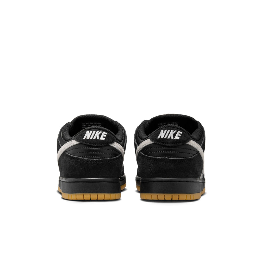 The NIKE SB DUNK LOW PRO BLACK/WHITE-BLACK-GUM LIGHT BROWN sneakers showcase a rear view with brown soles, white accents on the sides, and are crafted from premium materials for durable traction.