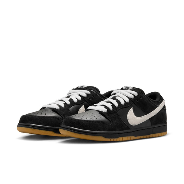 Nike SB Dunk Low Pro sneakers in black and white, featuring a gum light brown sole for durable traction, with white laces and swoosh logo.