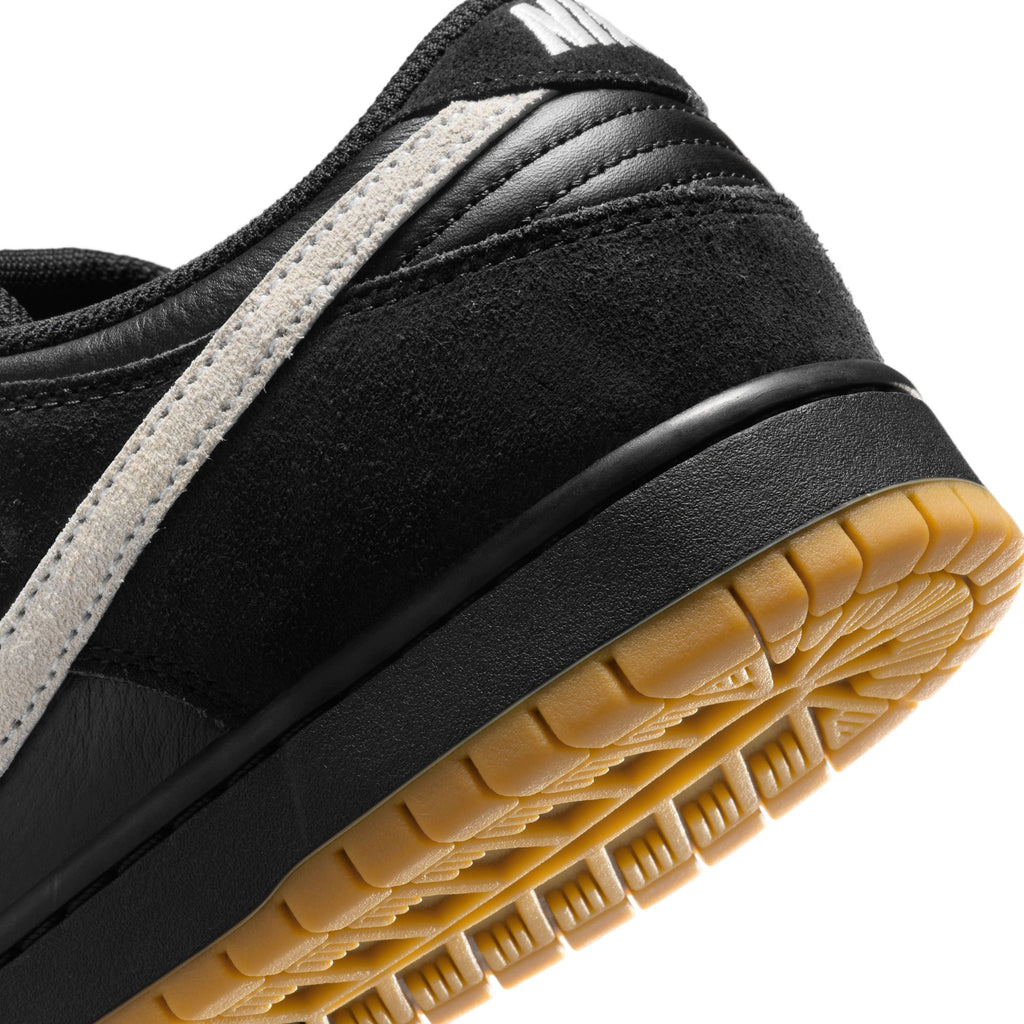 Close-up of the heel of the NIKE SB DUNK LOW PRO BLACK/WHITE-BLACK-GUM LIGHT BROWN, highlighting premium materials with a black midsole, white stripe, and gum-colored rubber outsole for durable traction.