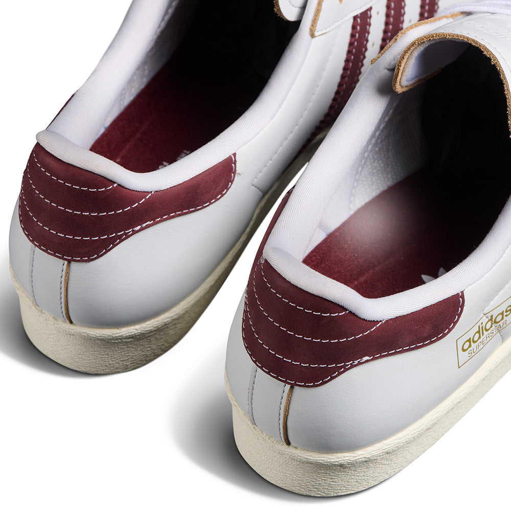 Close-up of the back and sides of the ADIDAS SUPERSTAR 80 ADV in Crystal White/Shadow Red, featuring gold branding and detailed heel and inner lining accents.