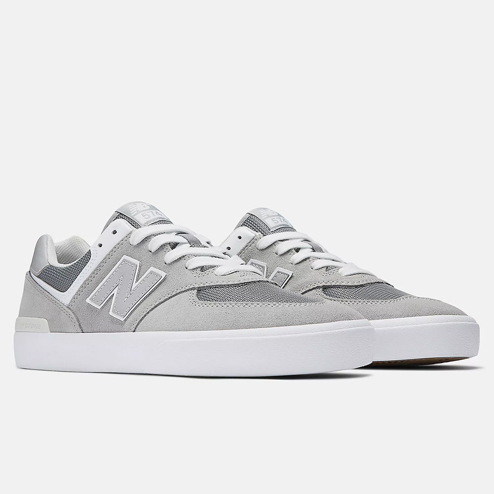 The NB NUMERIC 574 GREY / WHITE sneakers by NB NUMERIC showcase a gray and white design with an "N" logo, suede upper, and vulcanized sole. Reminiscent of the classic 574, they're perfect for skateboarding sessions. Displayed on a white background.
