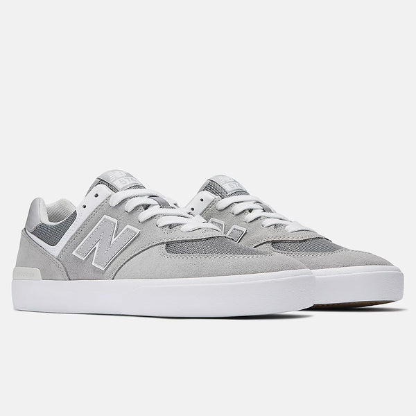 The NB NUMERIC 574 GREY / WHITE sneakers by NB NUMERIC showcase a gray and white design with an "N" logo, suede upper, and vulcanized sole. Reminiscent of the classic 574, they're perfect for skateboarding sessions. Displayed on a white background.