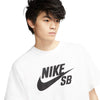 A young person wearing a white nike SB logo skate tee with an oversized logo on the front, a skate staple.