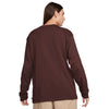 Man wearing a brown Nike 'City of Love' LS skate tee Earth, viewed from the back.