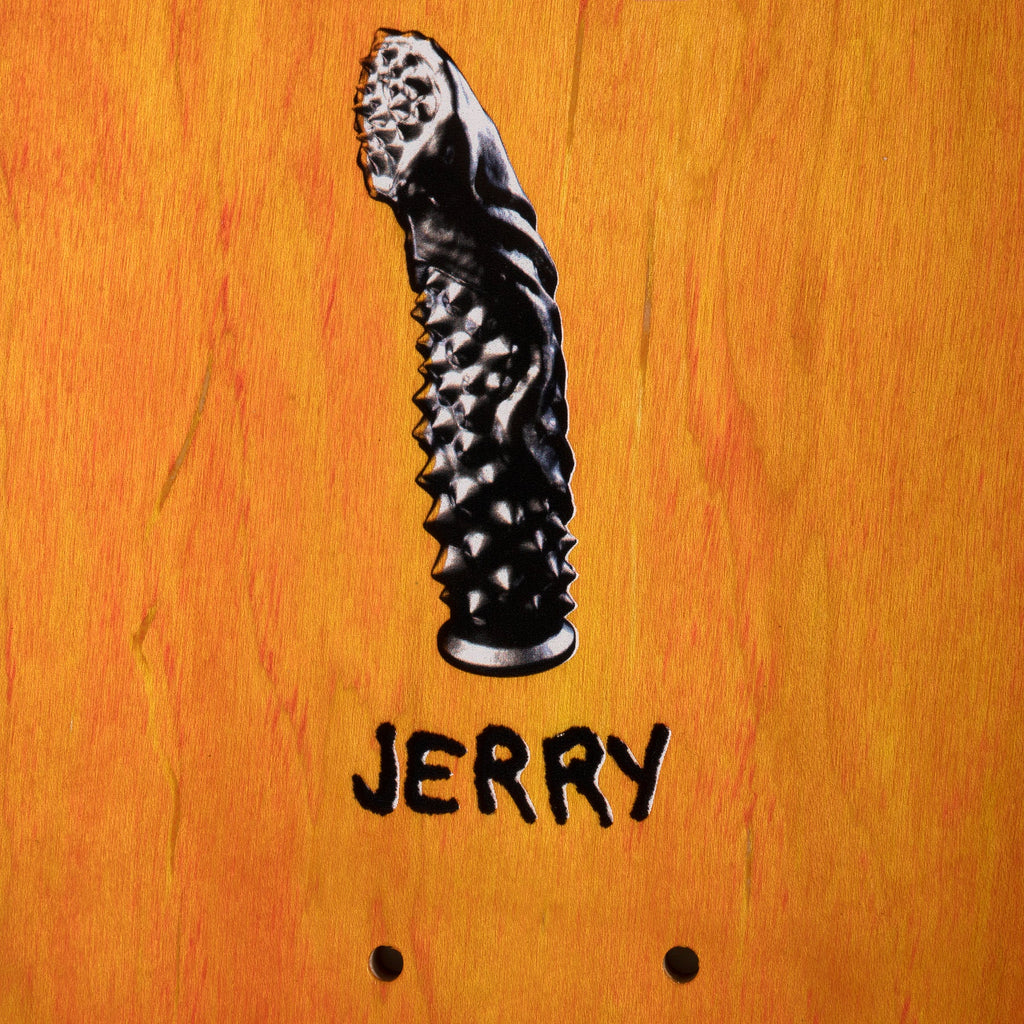 A close up of the top stained skateboard deck with an image of a black dildo and the name "jerry" underneath.
