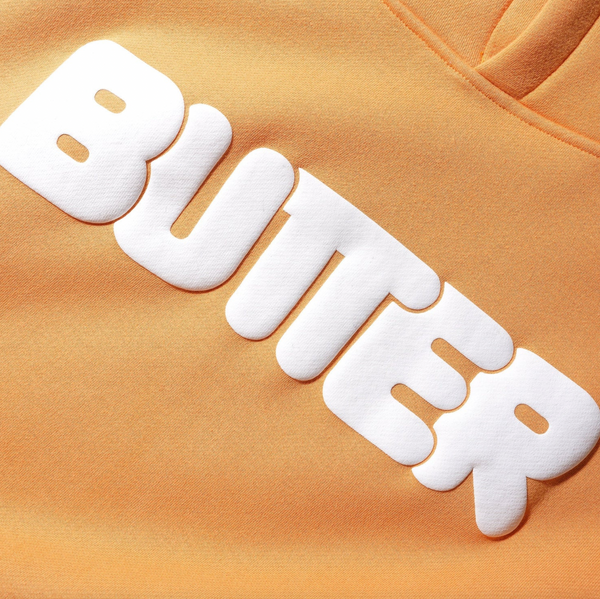 A close up of a Butter Goods Rounded Logo Hoodie Sorbet with the Butter Goods rounded logo on it.
