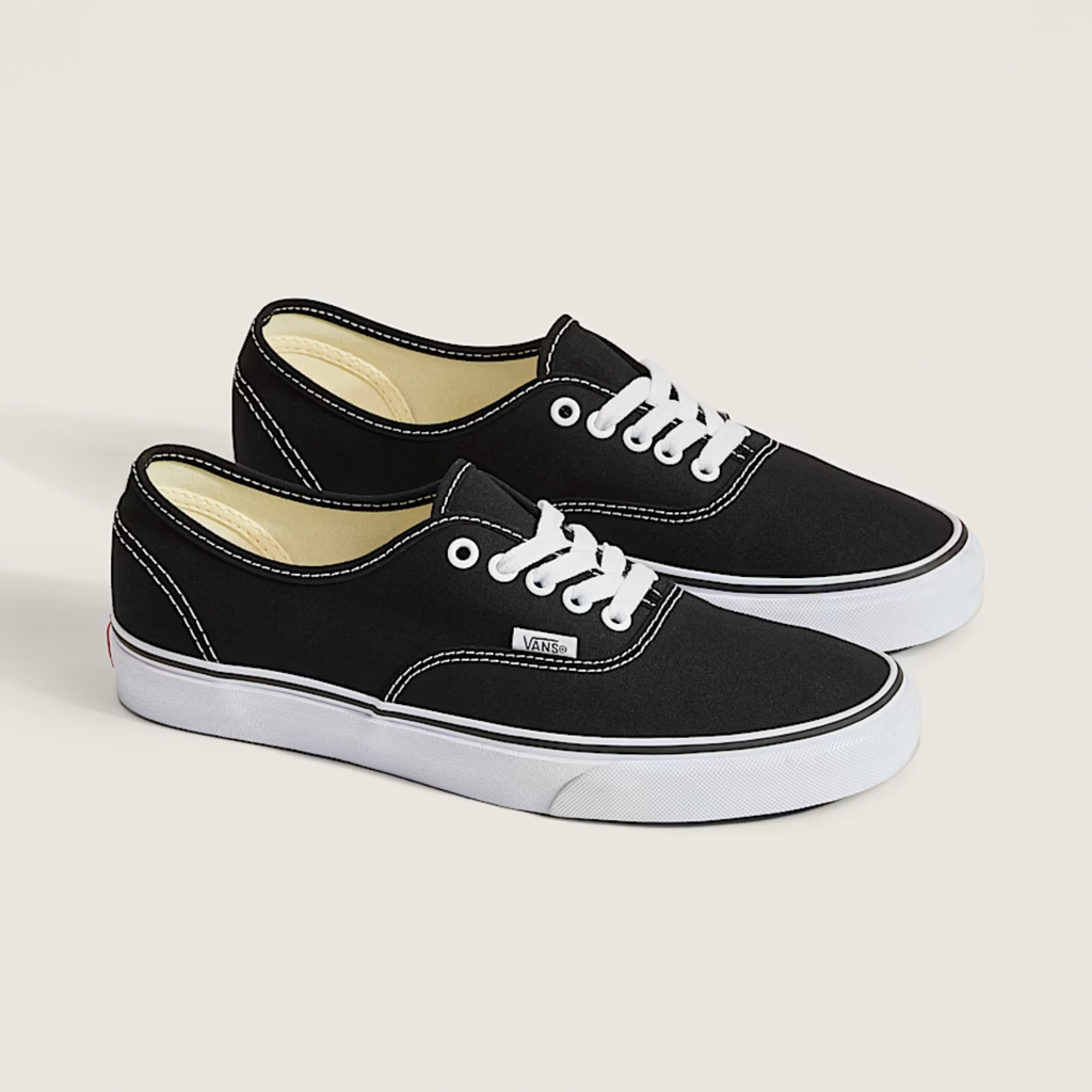 A pair of VANS AUTHENTIC BLACK / WHITE sneakers by VANS, featuring a classic low-top lace-up design with white soles and stitching, are displayed side by side on a neutral background.