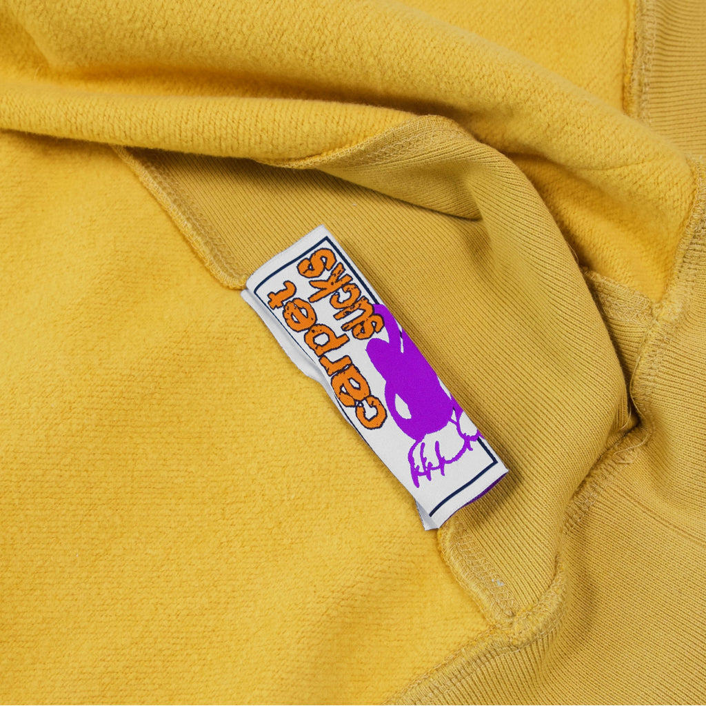 A CARPET BIZARRO ZIP HOODIE MUSTARD with a purple label on it, perfect for those who love unique fashion pieces.