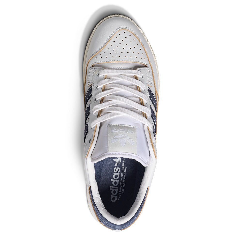 A top view of the ADIDAS CENTENNIAL 85 LOW ADV in Crystal White/Shadow Navy, featuring navy stripes, split suede details, white laces, a perforated toe box, and ADIDAS branding on the tongue and insole—ideal for skate style.
