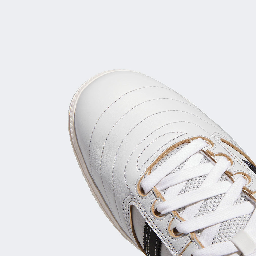 Close-up of the upper part of the ADIDAS BUSENITZ skateboarding shoe in Crystal White/Black/Off White, with matching laces, visible stitching, and black and tan accents, set against a plain light background.