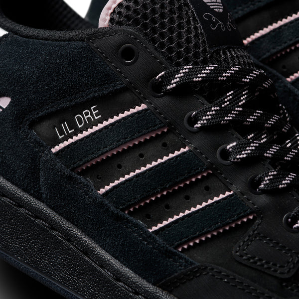 Close-up of a black sneaker with pink and black striped details and the text "ADIDAS CENTENNIAL 85 LO ADV X LIL DRE" on the side.
