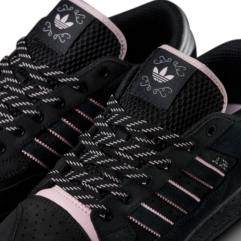Close-up of black ADIDAS CENTENNIAL 85 LO ADV X LIL DRE skateboarding shoes with pink accents, showcasing the knitted texture, laces, and brand logo on the tongue.