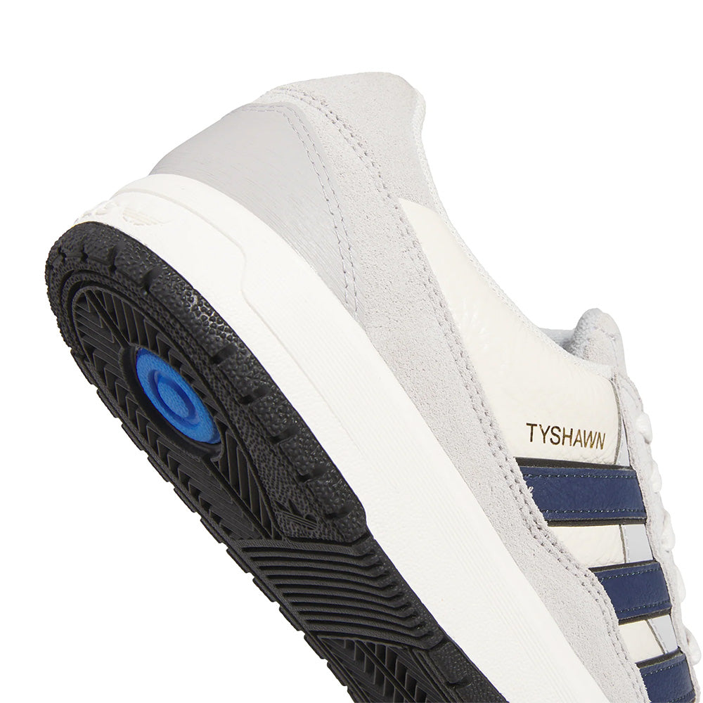 Meet the Adidas Tyshawn 2 Collegiate Navy/Grey: a sneaker with a black sole, blue stripes, and suede texture. Ideal for skateboarding, it boasts impact cushioning and features "TYSHAWN" on the side for extra style.