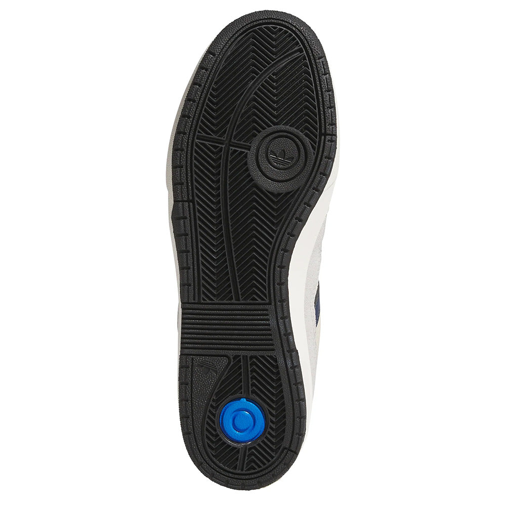 The image showcases the sole of an Adidas Tyshawn 2 Collegiate Navy/Grey sneaker, designed for skateboarding. It boasts a black tread pattern with a circular blue accent near the heel for enhanced impact cushioning, ensuring optimal comfort and performance.