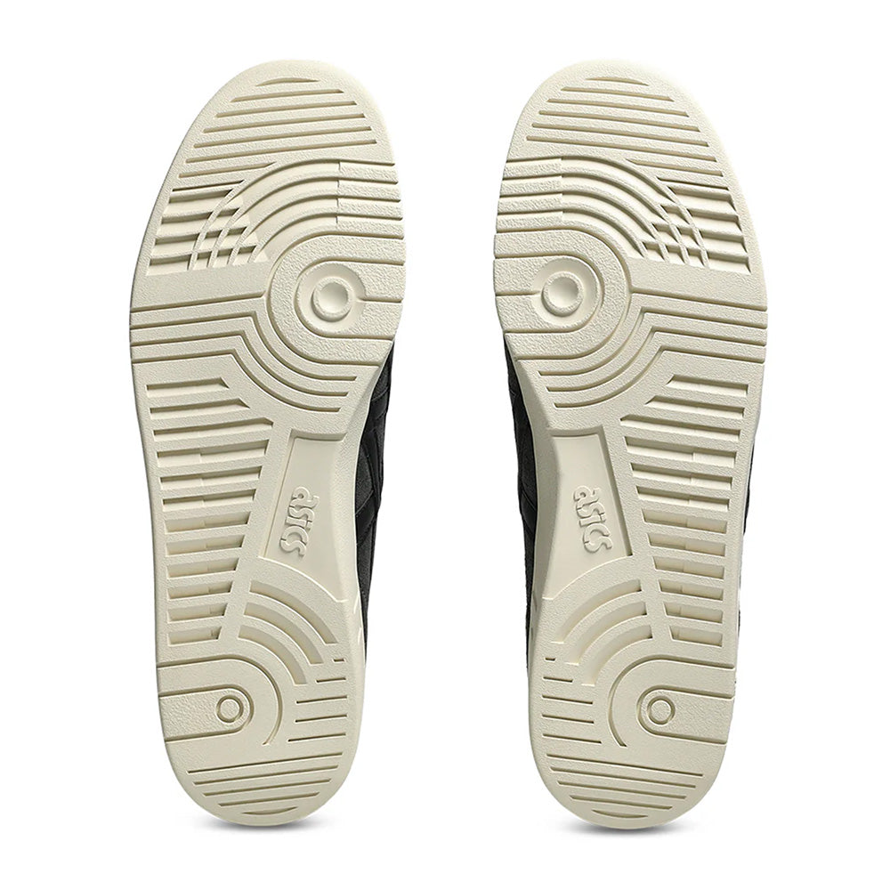 The image displays the soles of ASICS GEL-VICKKA PRO GRAPHITE GREY/BLACK shoes, featuring circular tread patterns and grooves, with "ASICS" visibly embossed. Enhanced by GEL technology, these beige soles combine durability and style.