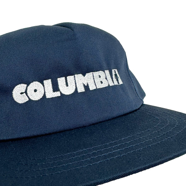 An embroidered navy GIRL X BLUETILE X COLUMBIA HAT with the word Columbia on it.