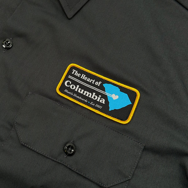 A black work shirt with a patch on it that says BLUETILE "HEART OF COLUMBIA" WORK SHIRT GREY by Bluetile Skateboards.
