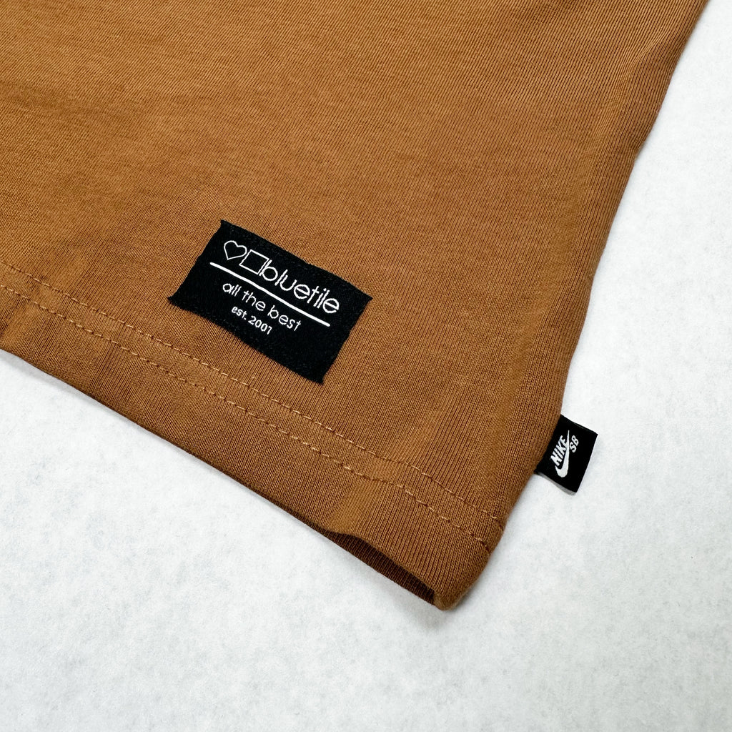 Close-up of a brown garment with a Bluetile Skateboards label and Nike tag.