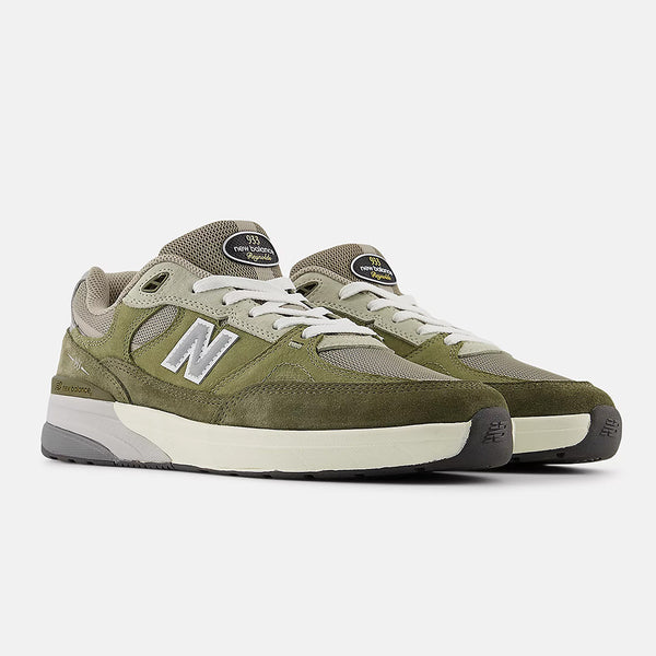 The NB NUMERIC REYNOLDS 933 GREEN by NB NUMERIC features an olive green and beige design, white laces, grey accents, and a thick ABZORB midsole for comfort inspired by classic skate shoes.