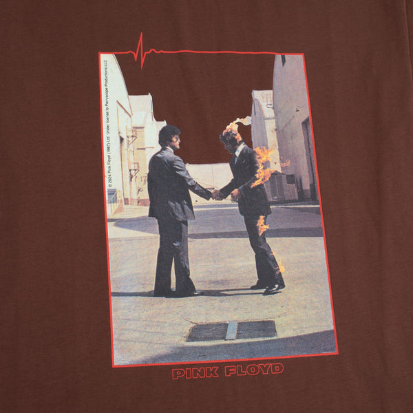 Image of a Pink Floyd "Wish You Were Here" album cover, showing two men in suits shaking hands, with one man on fire, overlaid on a premium brown shirt that reads "HABITAT X PINK FLOYD WISH YOU WERE HERE TEE BROWN" by HABITAT.
