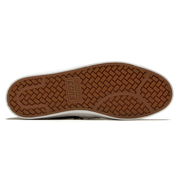 The bottom of a shoe with a brown rubber sole featuring a herringbone pattern and the Converse CONS logo embossed in the center.