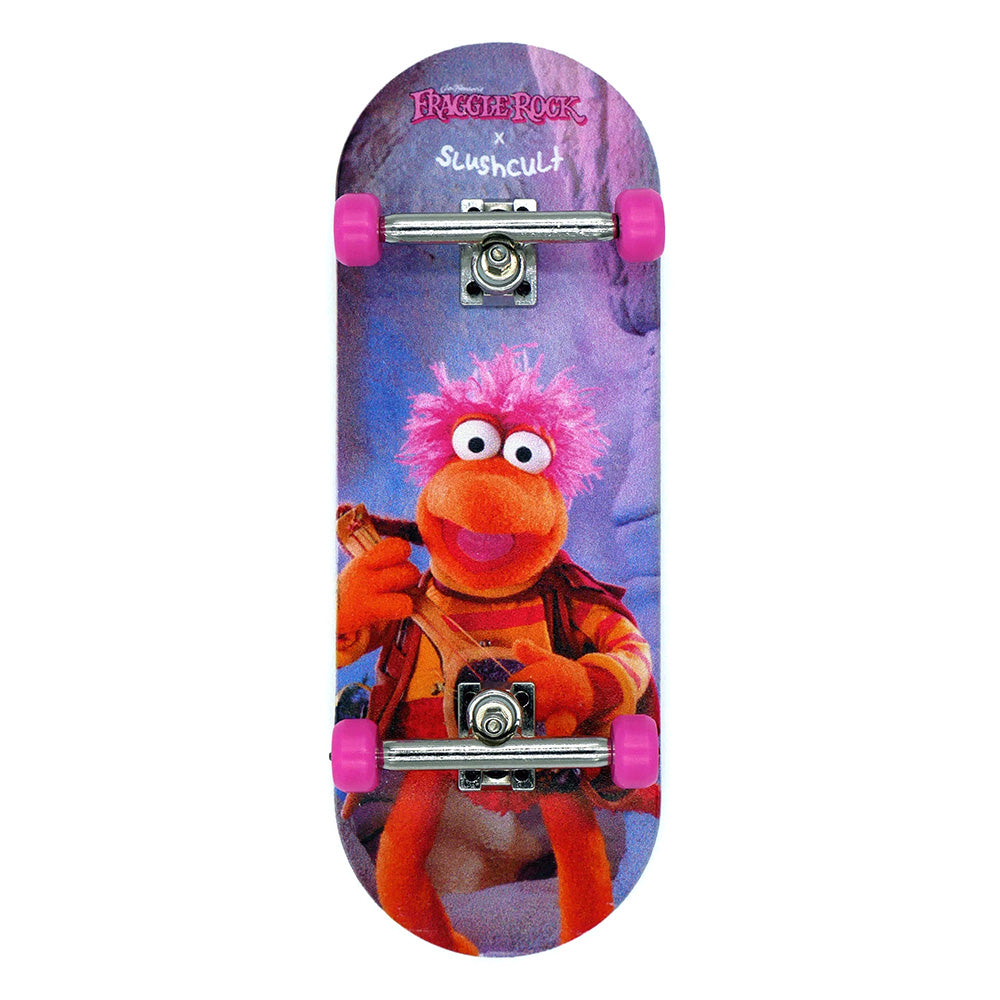 The SLUSHCULT X FRAGGLE FINGERBOARD GOBO by SLUSHCULT features a unique graphic, pink polyurethane wheels, and signature "Slushcult" branding—ideal for fingerboard enthusiasts and collectors.