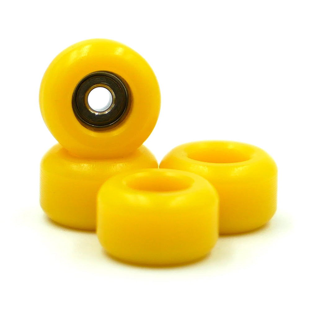 Four SLUSHCULT GROM FINGERBOARD WHEELS YELLOW are grouped together, with one wheel upright to showcase its precision bearings in the center.