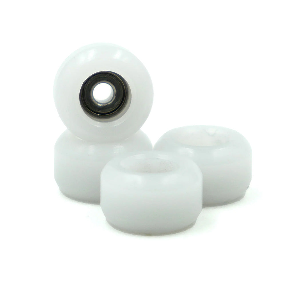 Four SLUSHCULT GROM FINGERBOARD WHEELS WHITE are displayed together, one upright to reveal its metal bearing—ideal for use with 34mm trucks or fingerboard trucks.