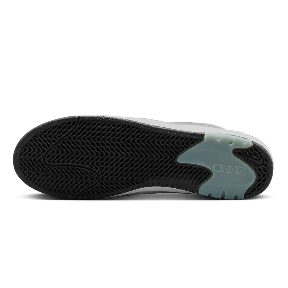The underside of the NIKE SB ISHOD 2 AIR MAX METALLIC SILVER / VARSITY RED sneaker features a black rubber sole with a wavy pattern and translucent teal near the heel, echoing the sleek design typical of the Nike SB Ishod 2 series.