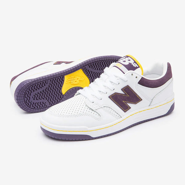 A pair of white NB NUMERIC 480 sneakers featuring ABZORB in-soles, with purple and yellow accents on a plain white background.