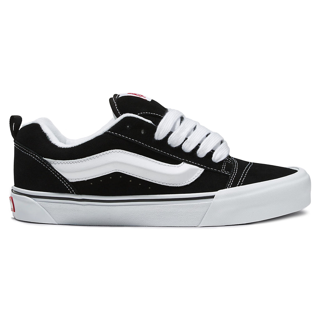 A black and white VANS KNU SKOOL BLACK / TRUE WHITE featuring a durable suede upper, a crisp white stripe on the side, white laces, and a thick white sole. It also includes a comfortable Popcush insole for added support.