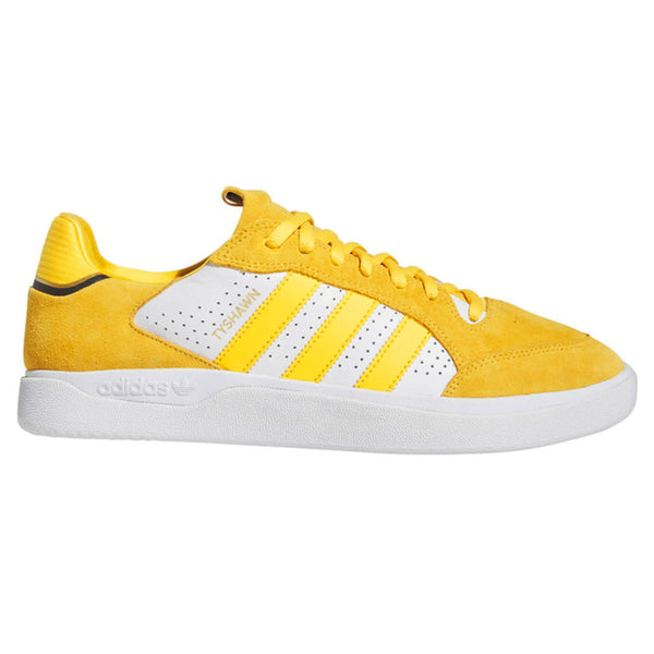 The ADIDAS TYSHAWN LOW BOLD GOLD / WHITE / BLACK sneaker features three iconic white stripes on the side, comes labeled "MYSHAWN" near the stripes, and has a sleek white sole.