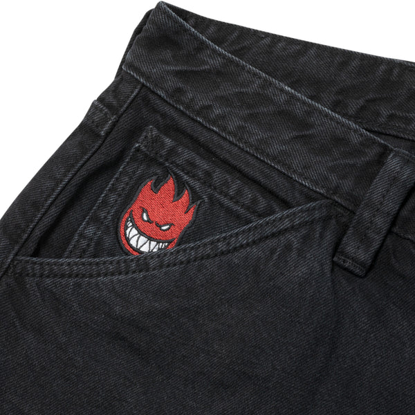 A pair of black denim jeans with a DELUXE SPITFIRE BIGHEAD FILL emblem on the pocket.