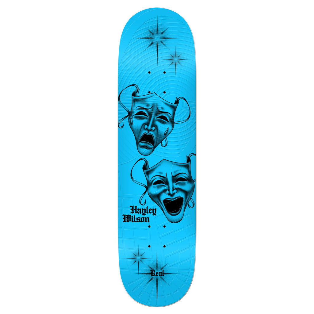 The REAL HAYLEY WILSON CRY LATER TRUE FIT by REAL is an 8.25" blue skateboard deck with two black-outlined theater masks, star accents, and the text "Hayley Wilson" and "Real.