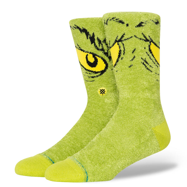 A pair of STANCE SOCKS X THE GRINCH "DA DA DAGRINCH" GREEN LARGE with yellow eyes on them.