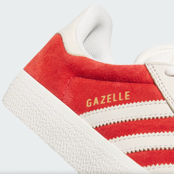 A close-up of the ADIDAS GAZELLE ADV sneaker in Better Scarlet and Chalk White shows "GAZELLE ADV" in gold on the side. The shoe features a suede material with a textured white sole and three iconic stripes on the upper.