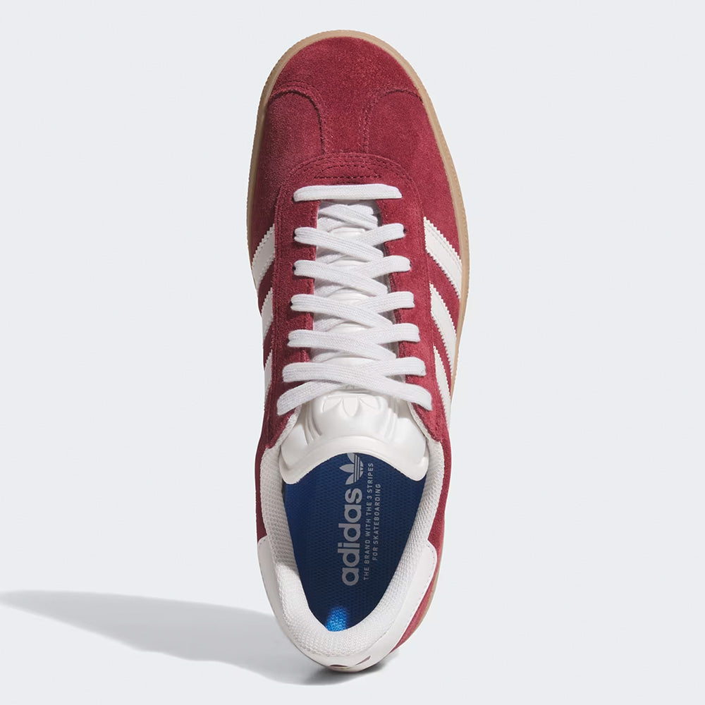 Top view of the ADIDAS GAZELLE ADV in Shadow Red, Crystal White, and Gold Metallic, featuring white laces, signature stripes, and a blue insole with the ADIDAS logo—a stylish and durable choice for skate shoe fans.
