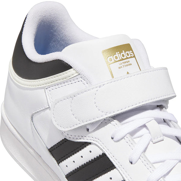 Close-up of the ADIDAS PRO SHELL FLAT WHITE / CORE BLACK sneaker, featuring black stripes, velcro strap, and gold branding—a classic leather basketball shoe inspired by heritage skateboarding styles from ADIDAS.