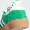 The Adidas Gazelle ADV in Green/Cloud White/Gold Metallic boasts water-repellent green suede, white stripes, a durable gum sole with a vulcanized rubber outsole, and features a bold white and gold logo on the heel.